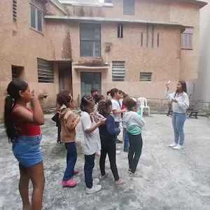 Educadora conduz atividade ao ar livre com crianças atendidas pela ONG na Biblioteca Escolar Municipal de Copacabana, Rio de Janeiro.
